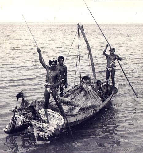 [Trobriand canoe poled by 3 standing Trobriand men displaying their Kula shell jewelry: 61k]
